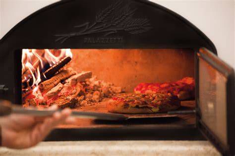 Famiglia che cucina la pizza nel forno esterno